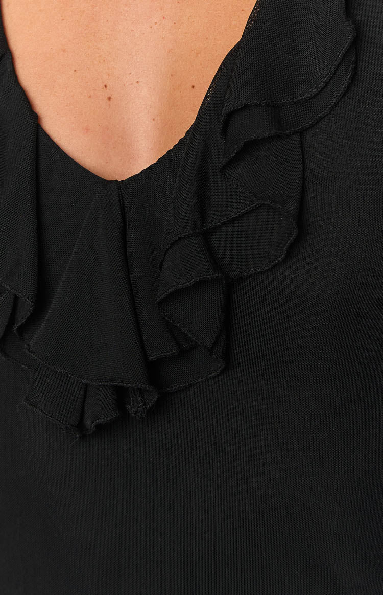 Close-up of the black V-neckline with layered ruffled trim in a fine knit fabric