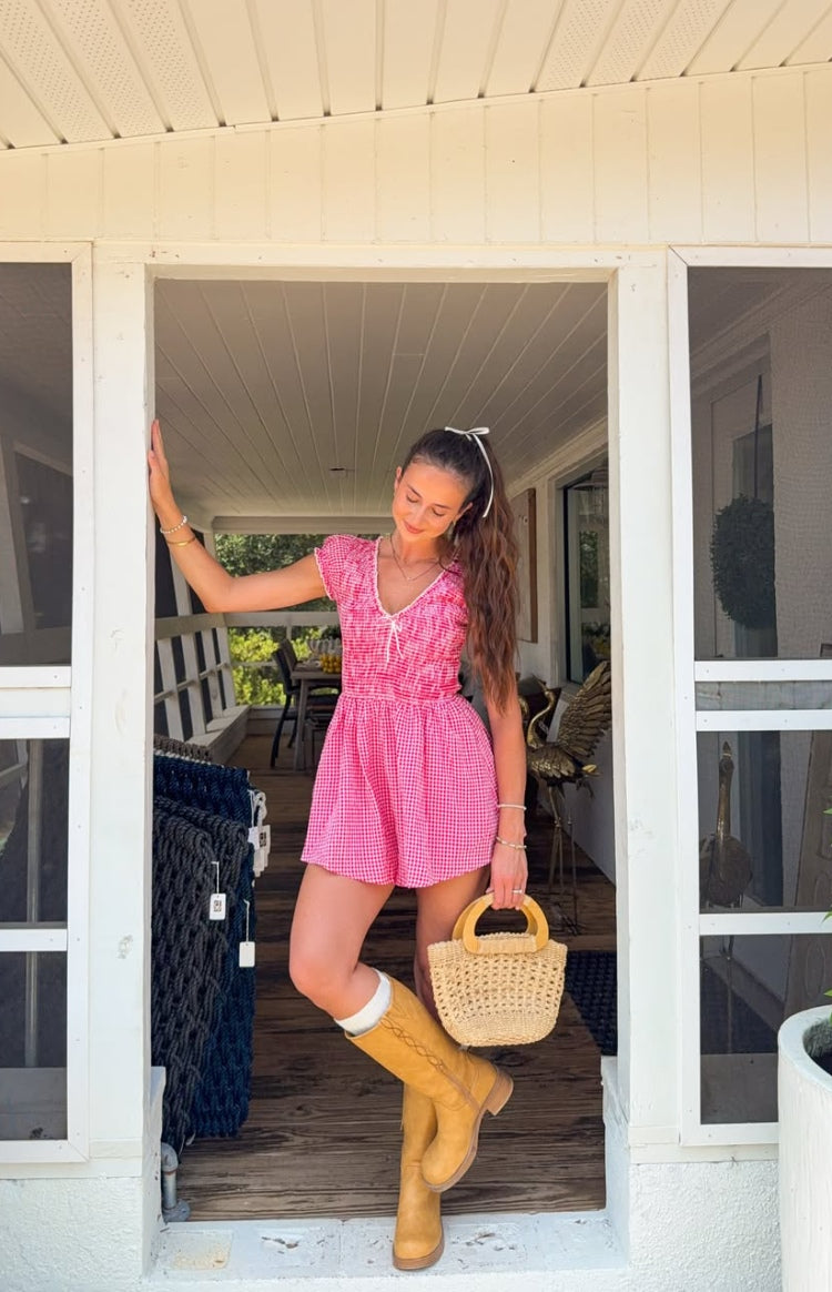 Full view of a red gingham playsuit with a V-neck, white lace trim, puff sleeves, and a shirred waist