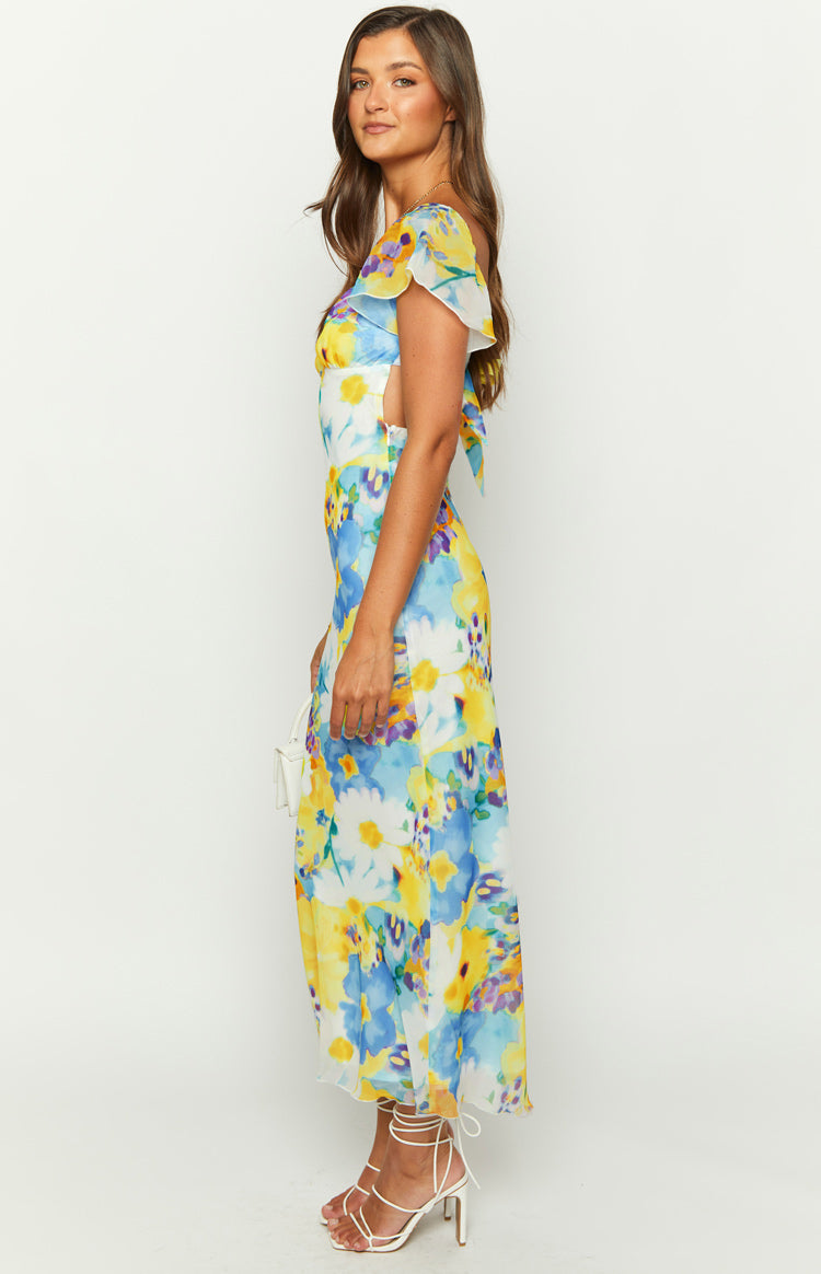 Side view of a blue floral chiffon maxi dress with flutter sleeves and waist cutouts