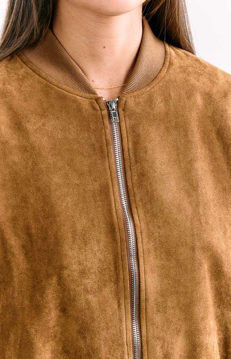 Close-up of the tan suedette fabric texture, silver zipper, and ribbed collar of the bomber jacket