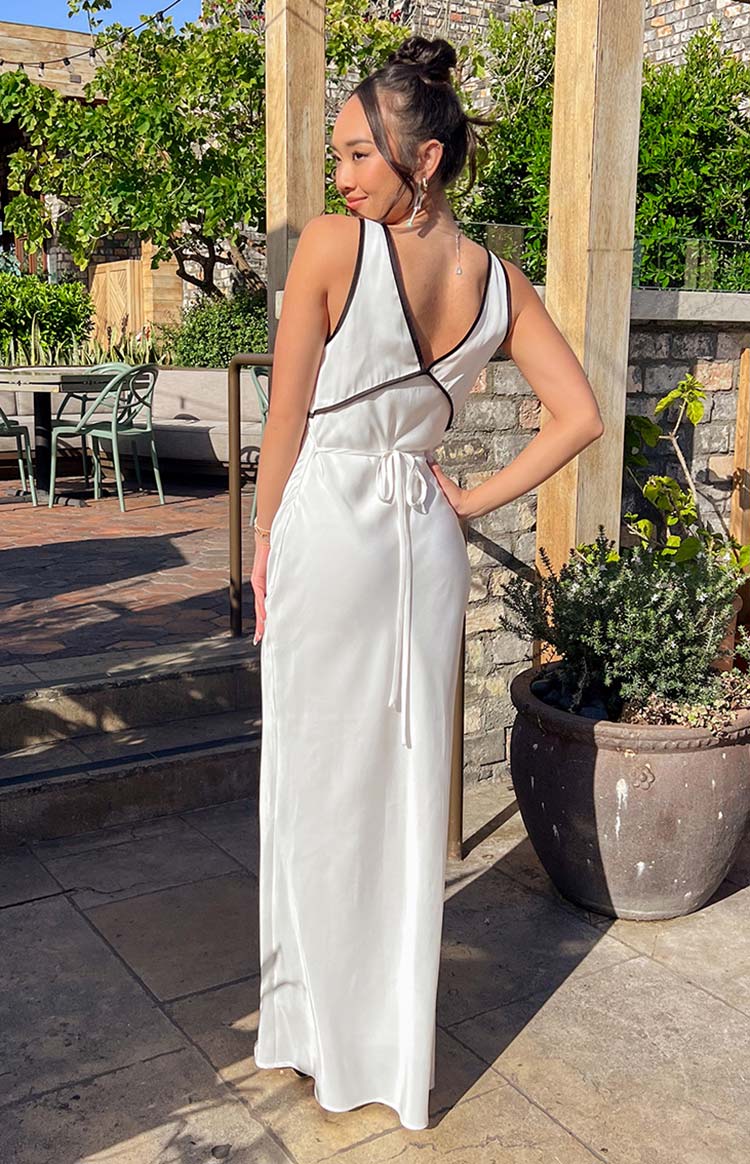 Rear view showing the black contrast trim on the V-neckline and the tie-back detail of a white maxi dress