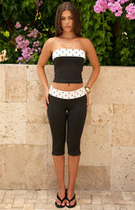 Black fitted capris with a white polka dot waistband and small side slits at the hem