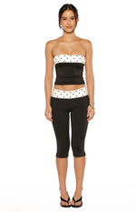 Fitted black capris with a white polka dot band at the waist, ending just below the knee