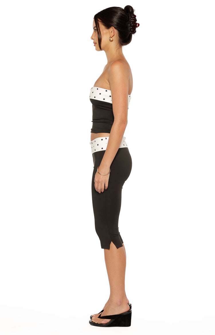 Side view of black fitted capris with a white polka dot waistband and small slits at the hem