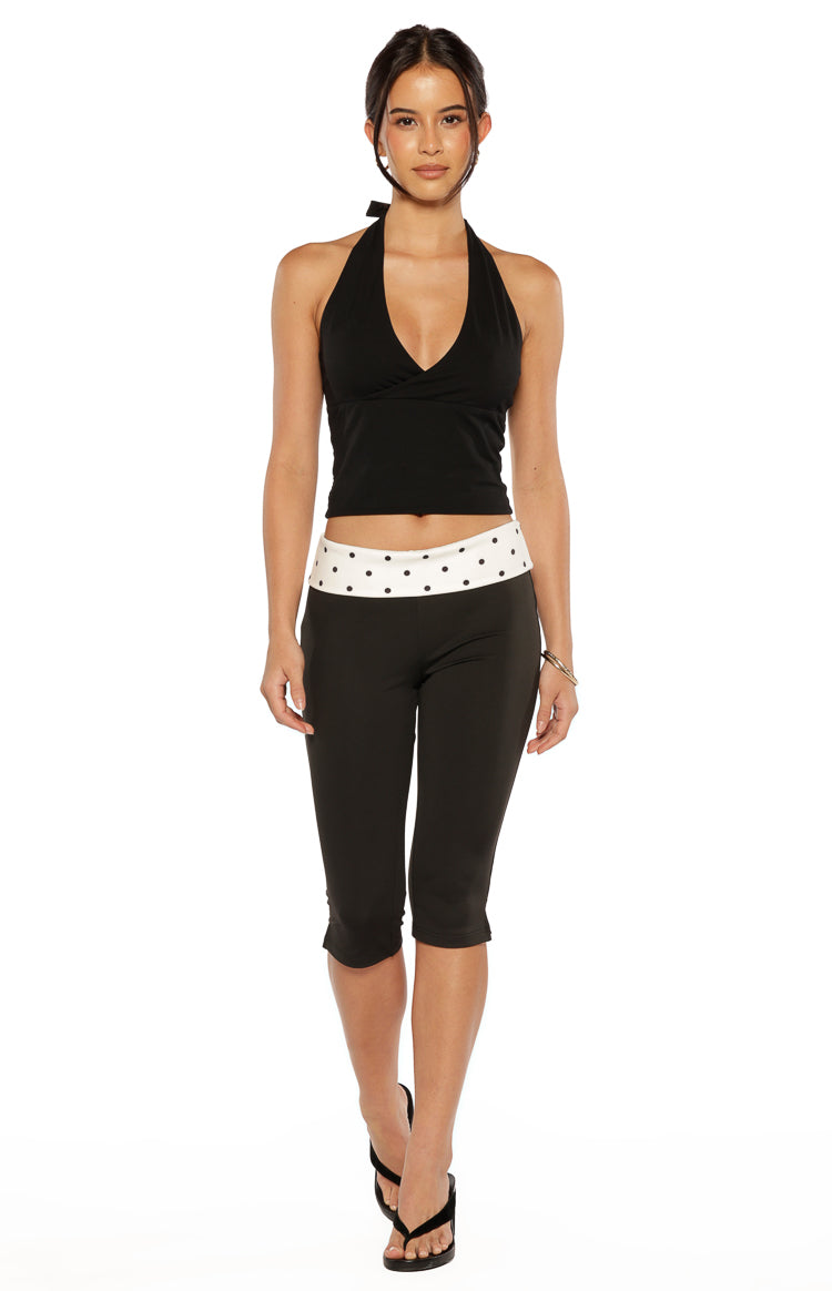 Black capris with a wide white waistband featuring black polka dots, cropped below the knee