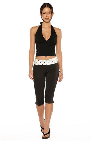 Black capris with a wide white waistband featuring black polka dots, cropped below the knee