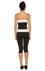 Rear view of a black strapless top with white polka dot bands at the top and bottom