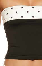 Close-up of the strapless top's white polka dot band transitioning to the solid black fitted body