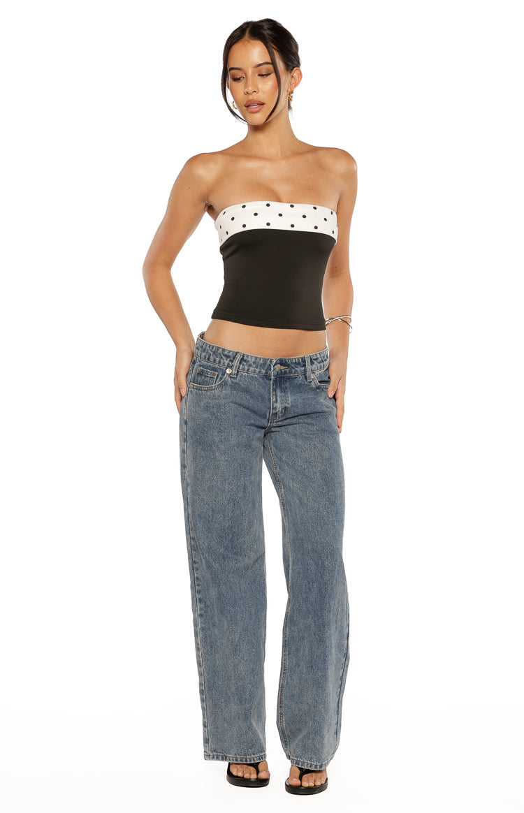 Front view of a black strapless top with a white polka dot band and a cropped hem