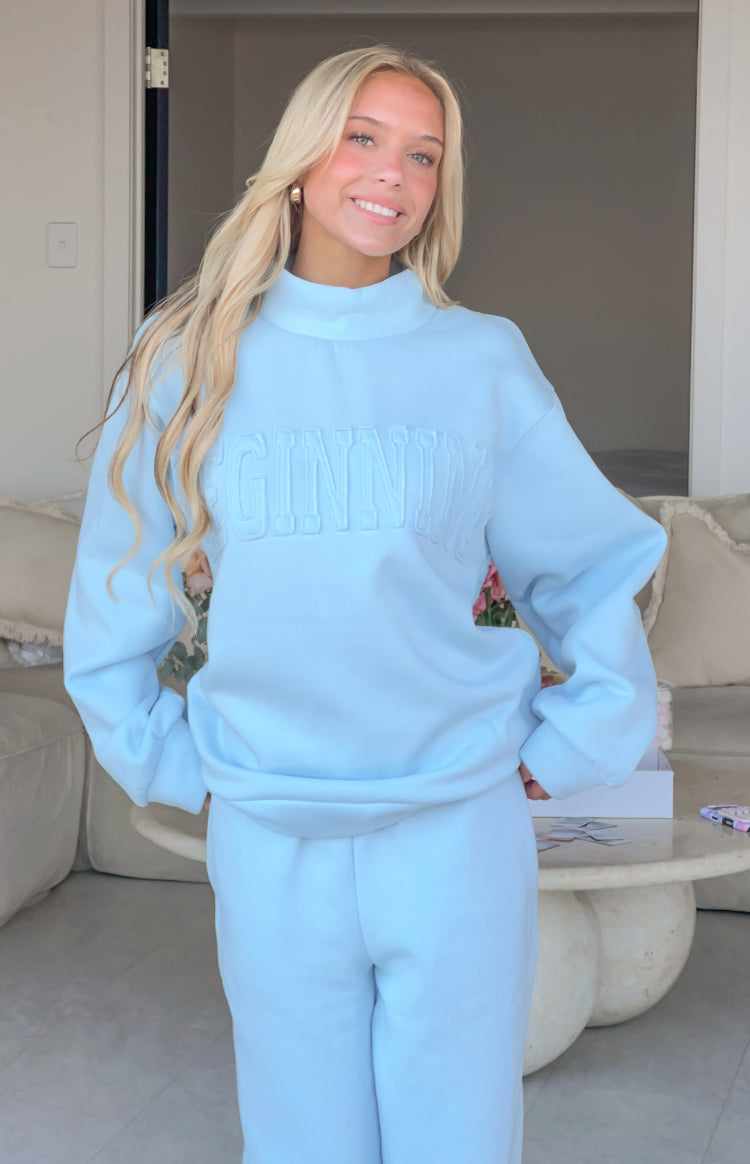 Light blue mock neck sweater with raised GINNI applique text on the chest and long sleeves