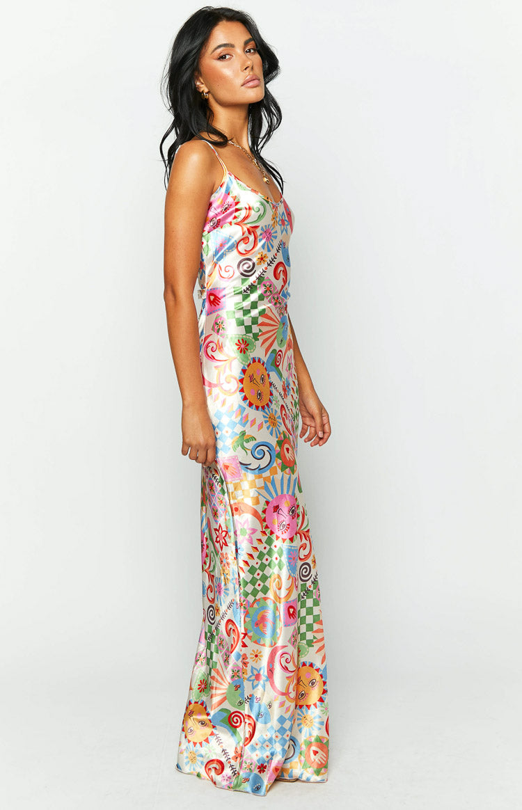 Side view of the full-length satin maxi dress, showcasing the vibrant summer print with sun faces, flowers, and checkerboard details