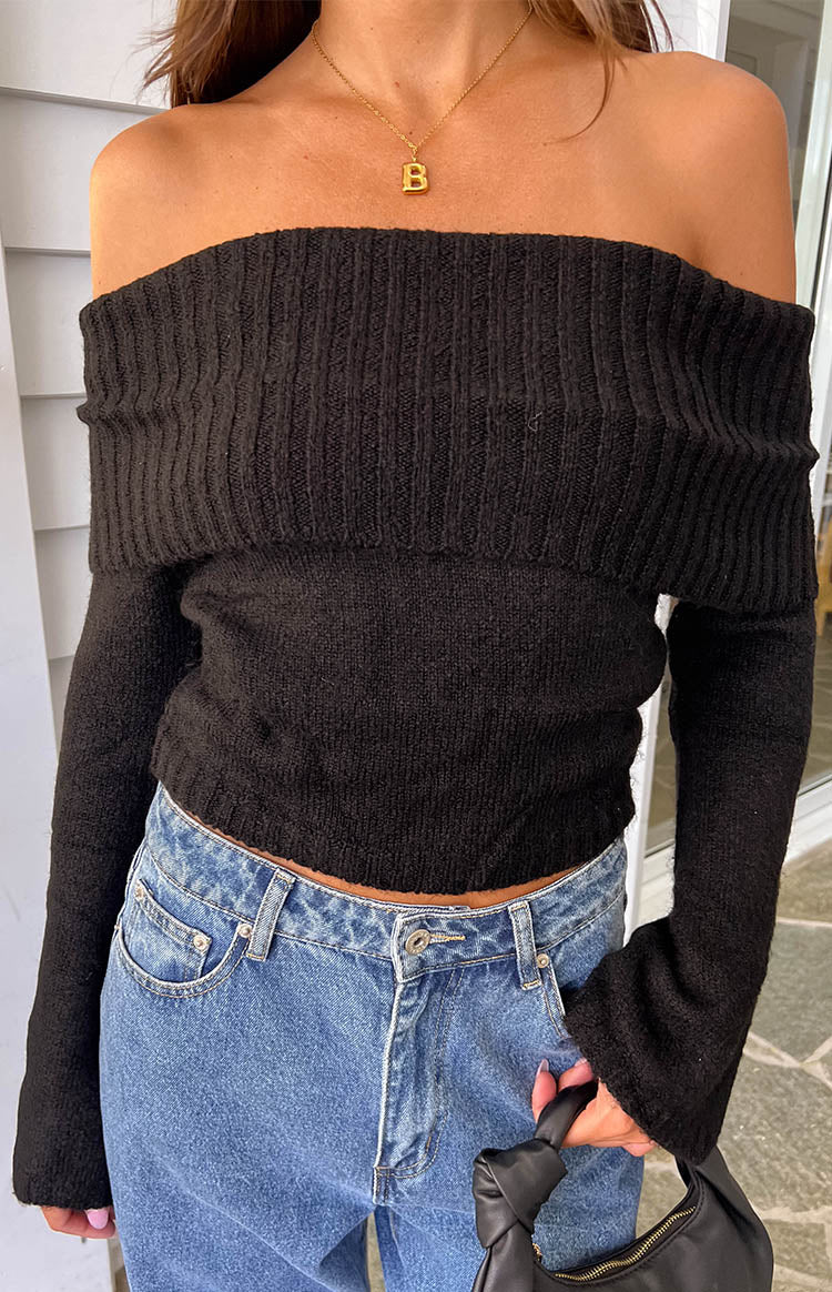 Black off-shoulder sweater with a wide ribbed fold-over neckline and long flared sleeves