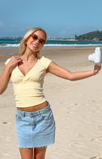 Cropped yellow polka dot jersey top with V-neck, short sleeves, and gathered empire waist