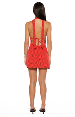 Rear view of a red polka dot mini dress with halter neck straps and an open tie-back detail