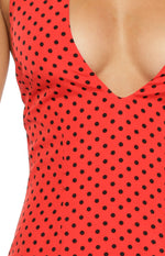 Close-up of the red fabric with black polka dots and the deep V-neckline of the mini dress