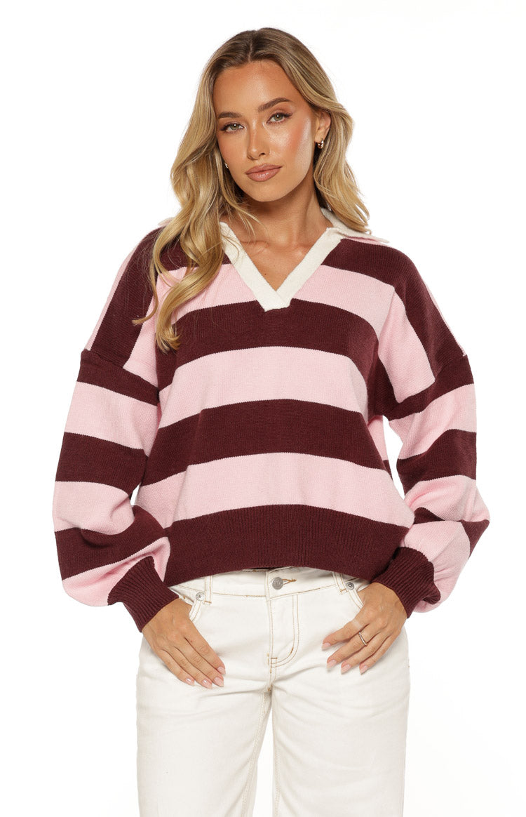 Front view of a pink and burgundy striped knit polo with a white V-neck collar and long cuffed sleeves