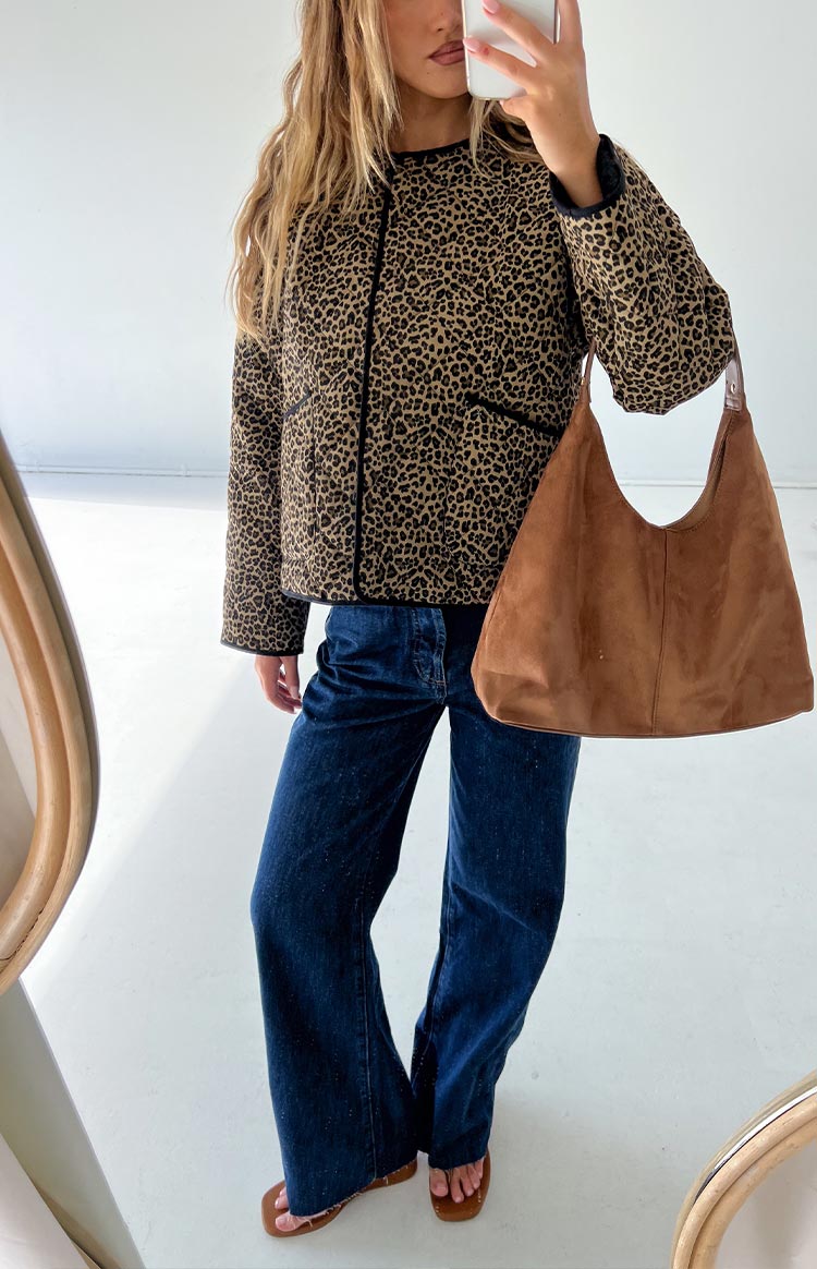 Front view of a beige and black leopard print quilted jacket with black piping and a round neckline