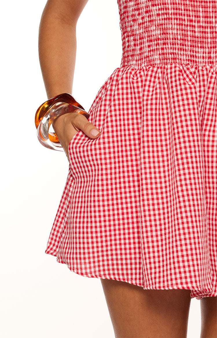 Close-up of the red gingham playsuit's smocked waistband and gathered shorts with a functional side pocket