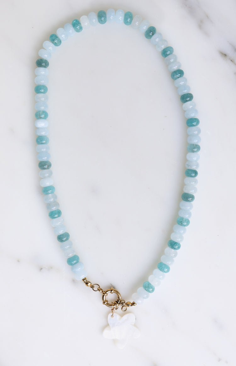 Beginning Boutique Roche Blue Beaded Flower Charm Necklace blue and light blue beaded necklace with a gold clasp and white fl