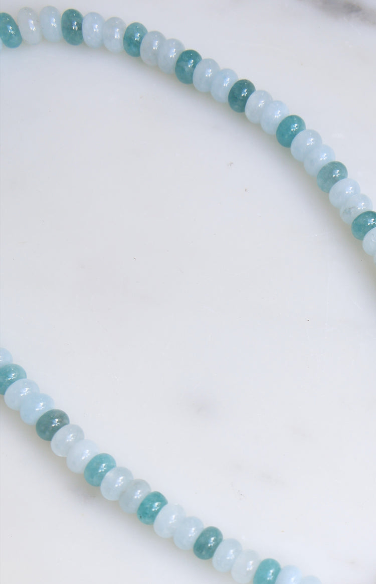 Close-up of the blue beaded necklace showing alternating light blue and teal round beads