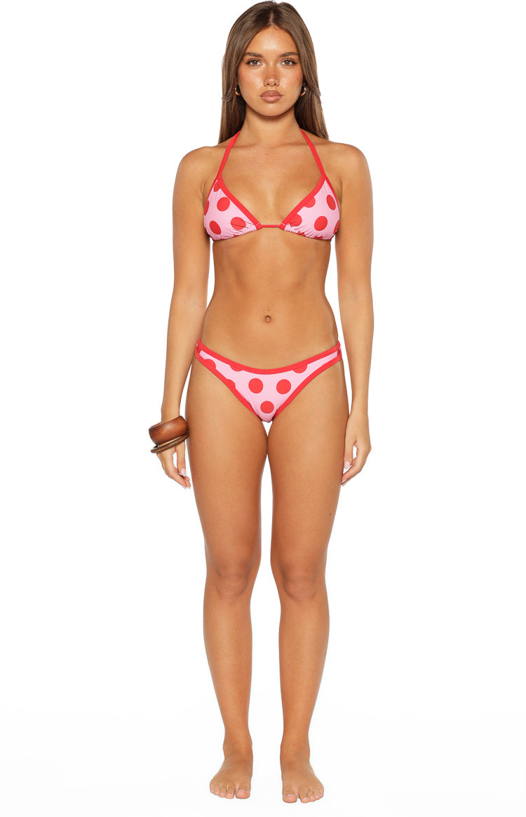 Front view of pink bikini bottoms with red polka dots and red contrast binding, cheeky cut