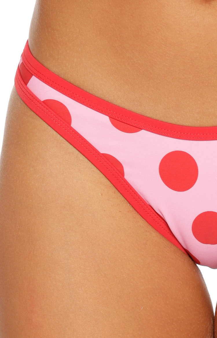 Close-up of the side of pink and red polka dot bikini bottoms with red contrast binding
