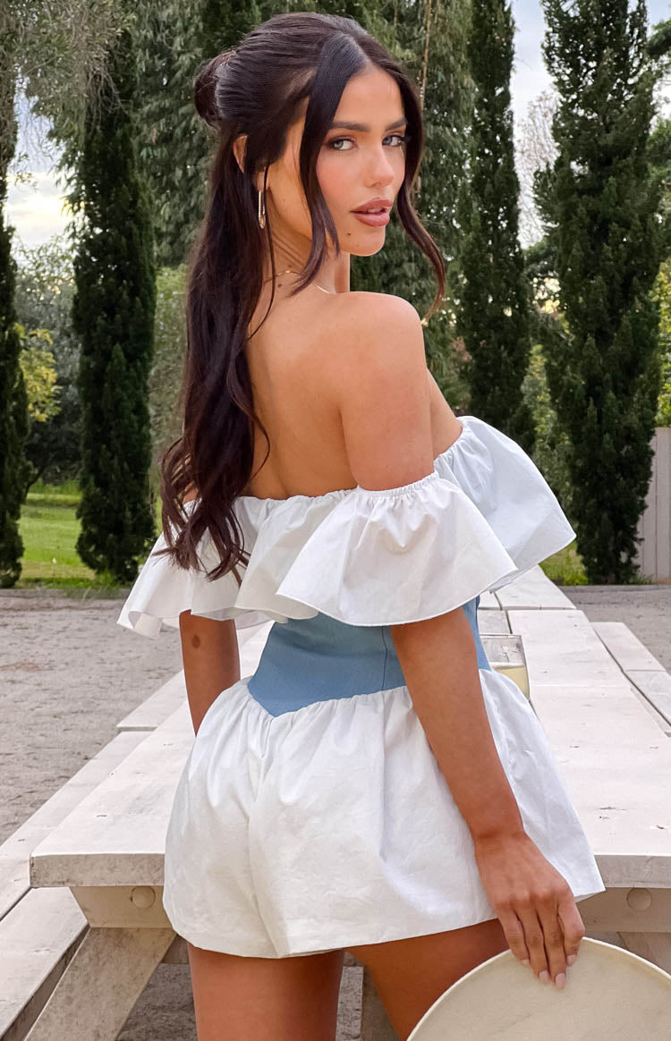 Rear view of the off-shoulder white ruffled sleeves, light blue denim waist, and voluminous white shorts