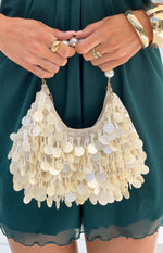 Close-up of cream beaded handbag with dangling mother-of-pearl discs and a large pearl top handle
