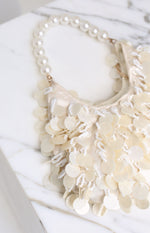 Close-up of a cream pearl beaded handbag with mother-of-pearl discs and white seed bead fringes