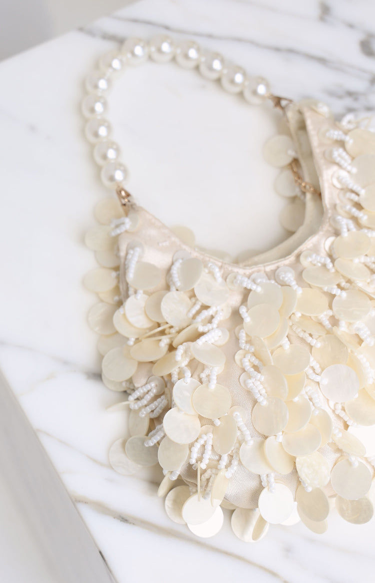Close-up of a cream pearl beaded handbag with mother-of-pearl discs and white seed bead fringes