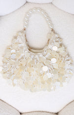 Cream handbag featuring a pearl beaded handle and layered mother-of-pearl disc and seed bead embellishments
