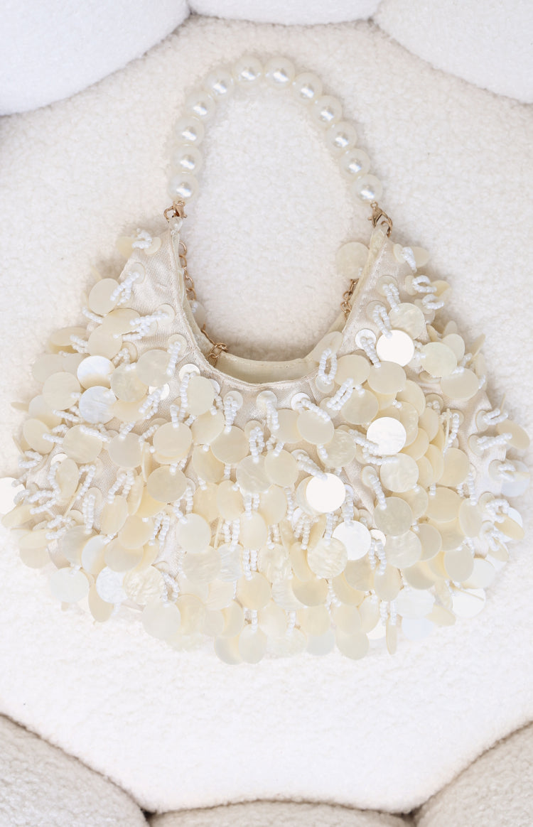 Cream handbag featuring a pearl beaded handle and layered mother-of-pearl disc and seed bead embellishments