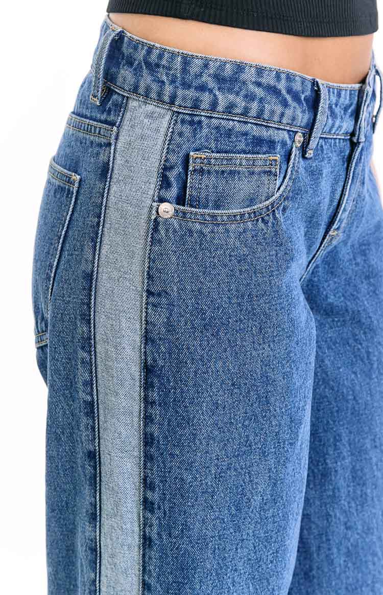 Close-up of mid-wash denim jeans with a lighter contrast stripe down the side and front coin pocket