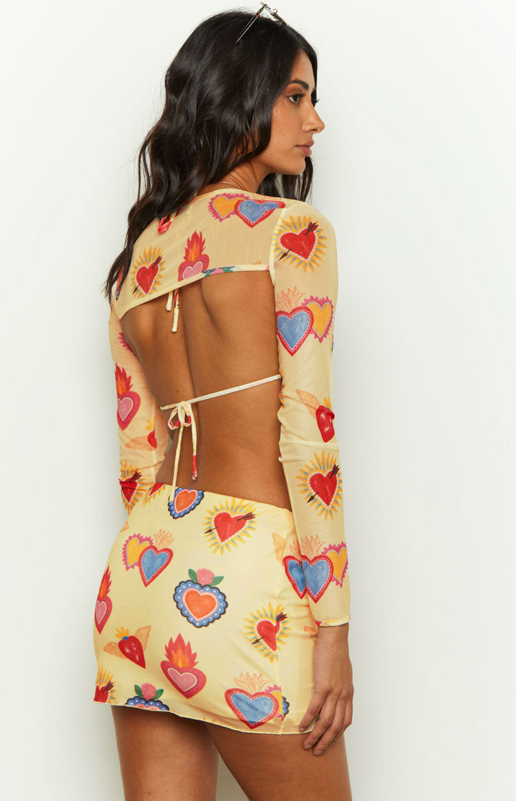 Side view of a yellow mesh mini skirt featuring a vibrant, colourful heart print