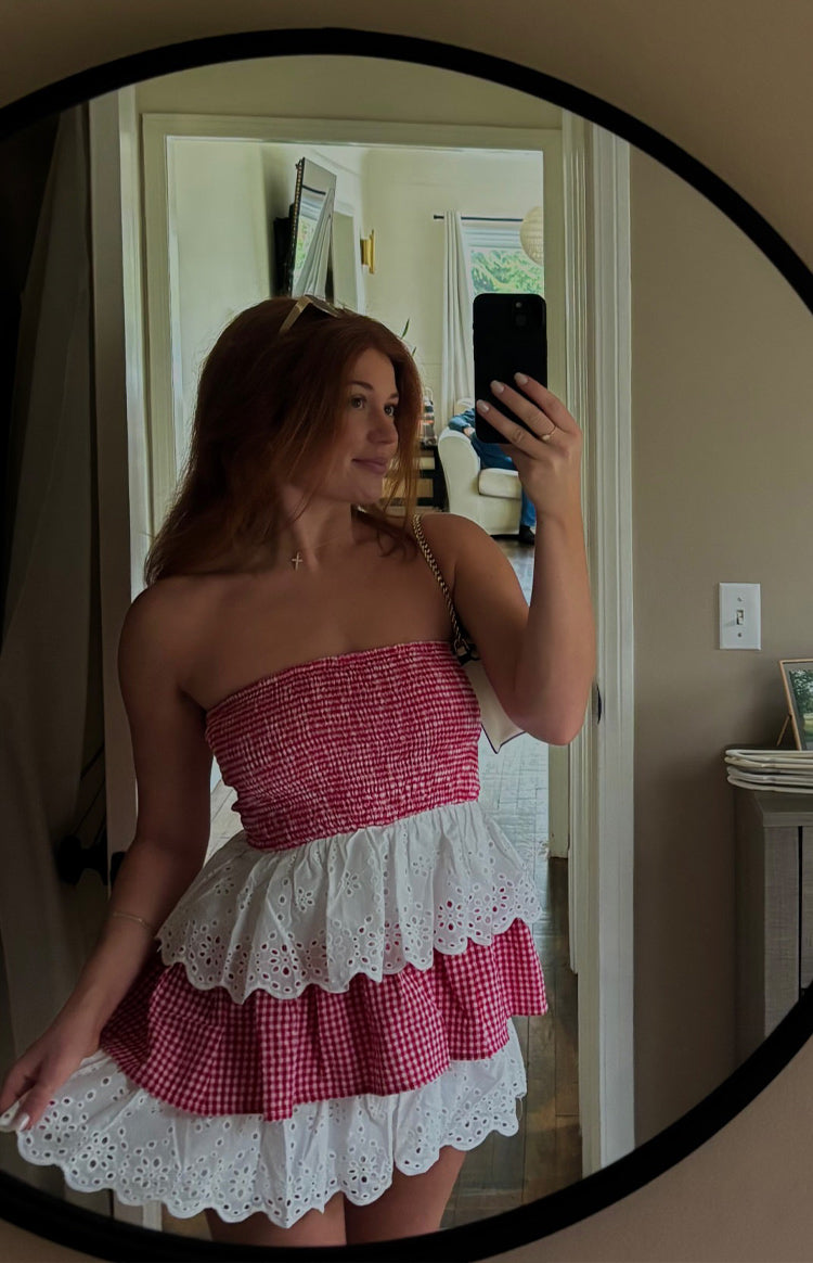 Front view of the red and white strapless mini dress showing the smocked bodice and tiered broderie anglaise skirt