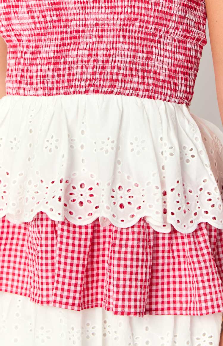 Close-up of the red and white gingham shirred bodice transitioning to a white broderie anglaise ruffle and gingham skirt