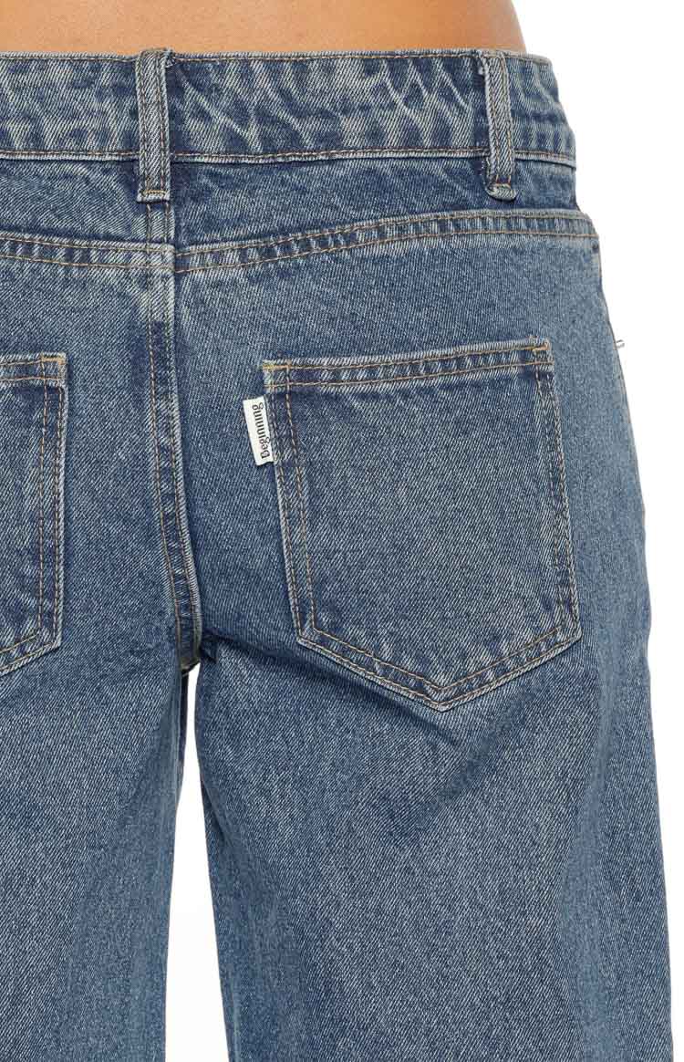 Close-up rear view of mid-wash blue denim jeans showing the two back patch pockets, waistband, and belt loops