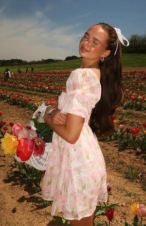 Side view of a pink floral babydoll mini dress with sheer overlay fabric and short puff sleeves