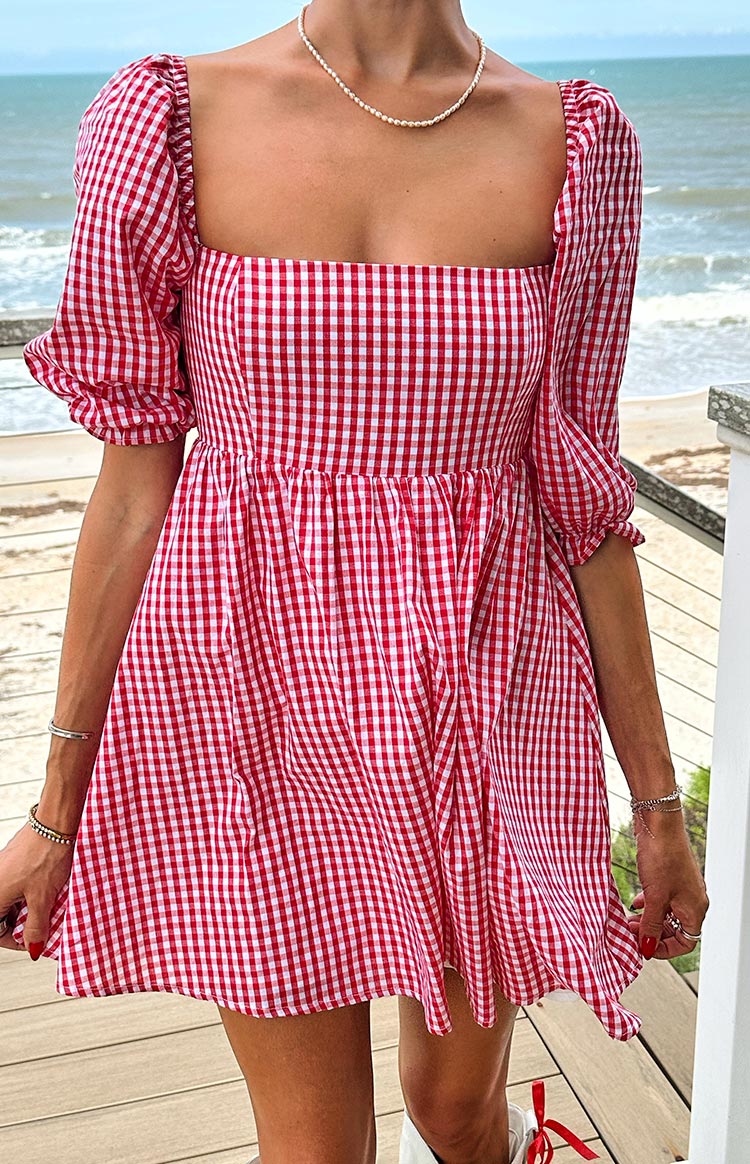 Close-up of the square neckline and puffed sleeves of a red gingham babydoll mini dress