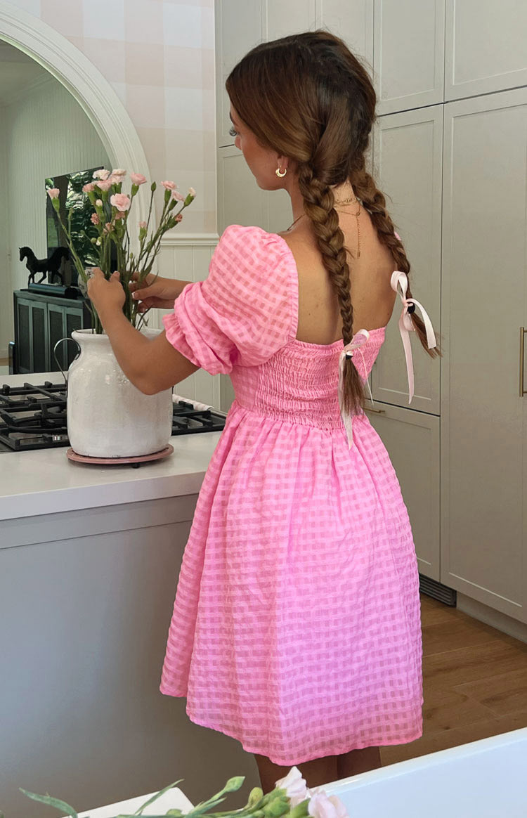 Rear view of a pink checked babydoll mini dress with a square back and shirred bodice