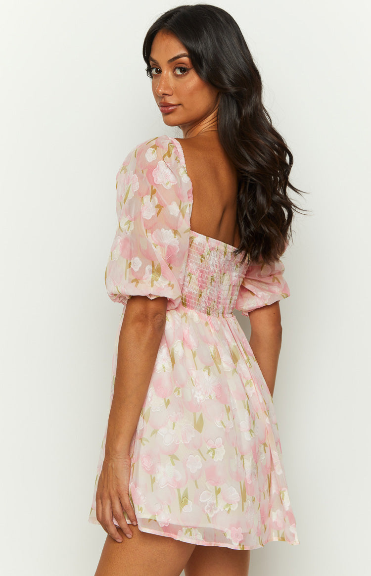 Rear-side view of a pink floral babydoll mini dress with a smocked back and puff sleeves