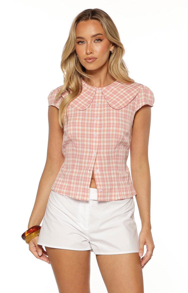 Front view of a pink plaid top with a Peter Pan collar, short puff sleeves, and a button-front closure