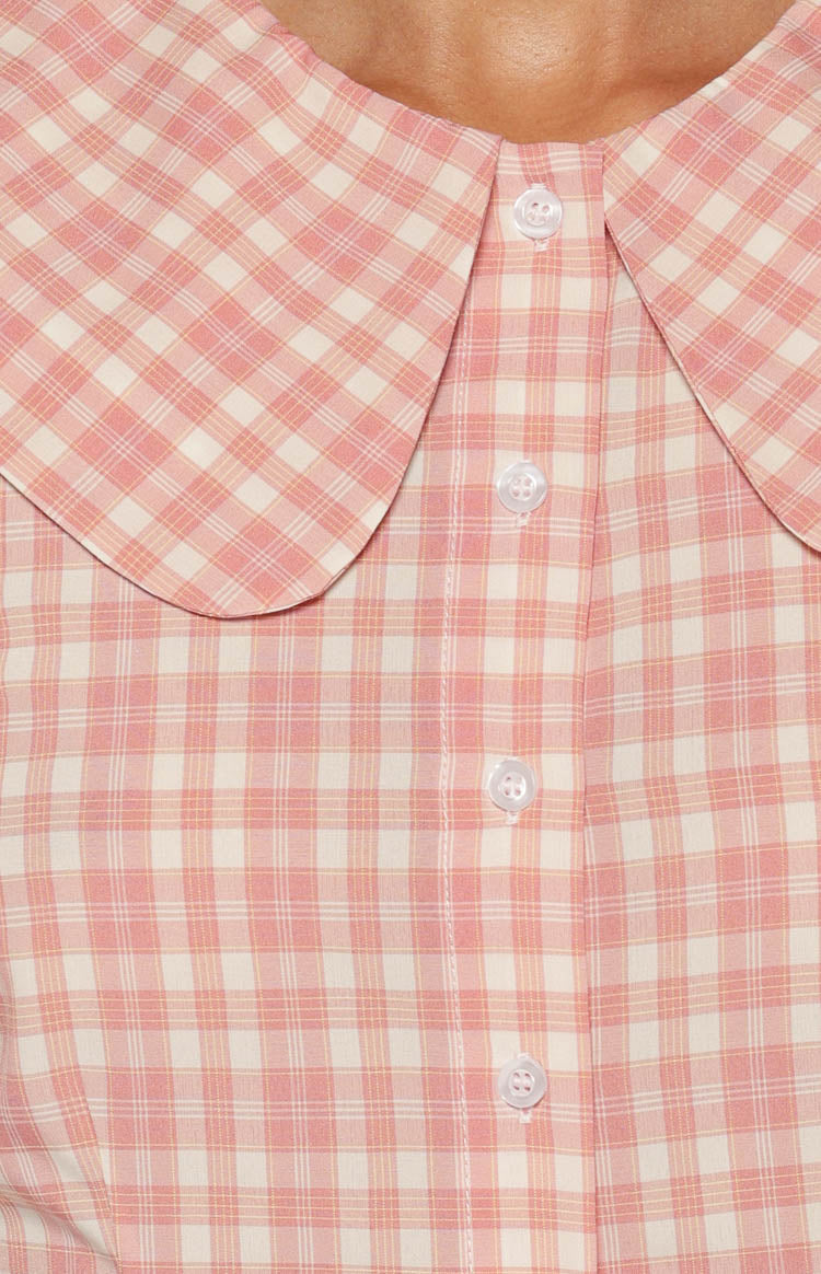 Close-up of the pink plaid Peter Pan collar and white button-front placket of the top