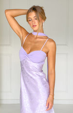 Close-up of the lilac maxi dress with a twisted solid bust, floral satin skirt, thin spaghetti straps, and scarf neckline