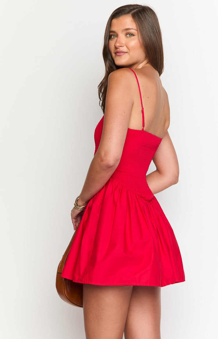 Side view of the red mini dress with a smocked bodice, thin spaghetti straps, and a gathered mini skirt