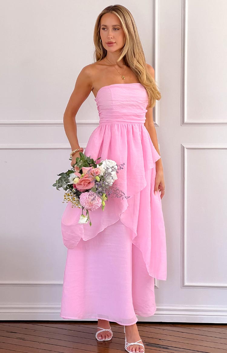 Pink strapless maxi dress with a ruched bust, gathered waist, and a flowy tiered skirt with a sheer overlay