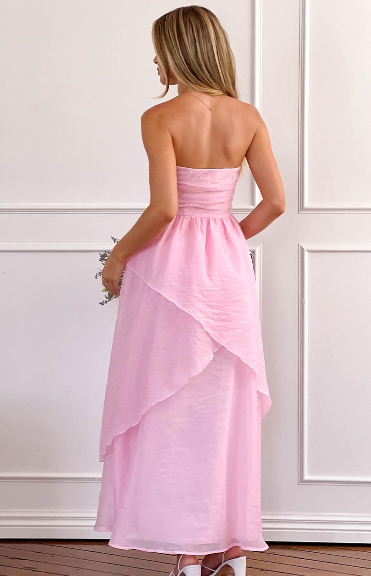 Rear view of a pink strapless maxi dress with a ruched bodice and a layered, asymmetrical skirt in sheer crinkled fabric