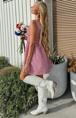 Side profile of a red gingham mini dress with a smocked bodice and a full, flared skirt