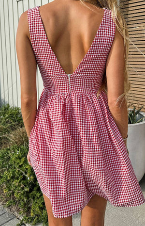 Rear view of a saffron red gingham mini dress with a deep V-back and white zipper closure