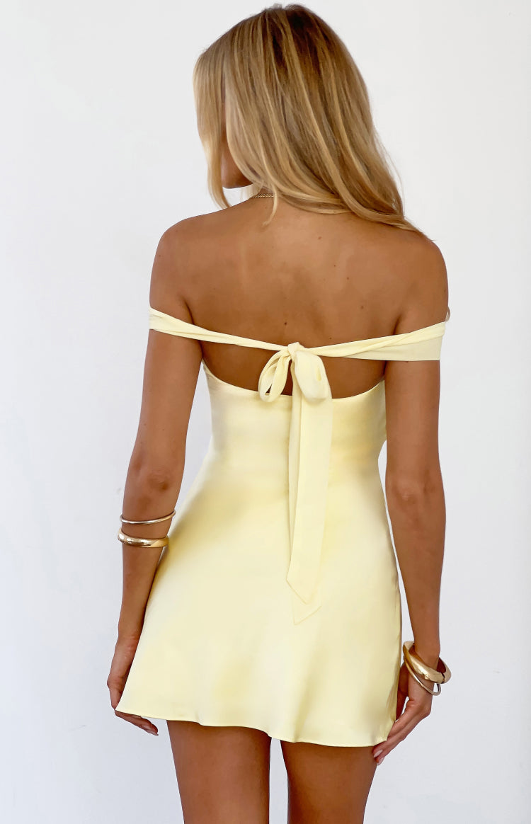 Rear view of a yellow off-shoulder mini dress with a tie-back detail forming a bow